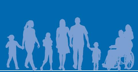A group of adults and children in silhouette form standing against a darker blue background. One adult is in a wheelchair and tended to by another adult.